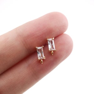 May include: Two gold-toned earring findings with clear rectangular crystal stones.