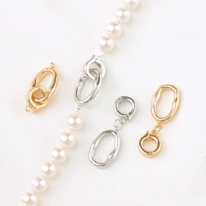 May include: A close-up of five different gold and silver clasps for jewelry making. The clasps are on a white background.