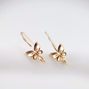 Peut inclure: Une paire de crochets d'oreille en forme de papillon dorés. Les crochets sont en métal et présentent un motif de papillon. Le papillon est détaillé avec des ailes et un corps.