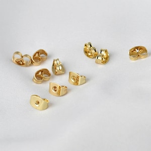 Puede incluir: Un juego de 10 respaldos para pendientes de color dorado. Los respaldos están hechos de metal y tienen un acabado liso. Están diseñados para adaptarse a los postes de pendientes estándar.