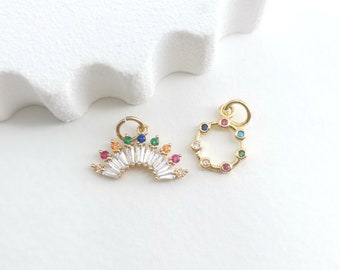 May include: Two gold charms featuring colourful gemstones. One charm is a rainbow arch with clear baguette-shaped stones and colourful round stones. The other charm is a circle with colourful round stones.