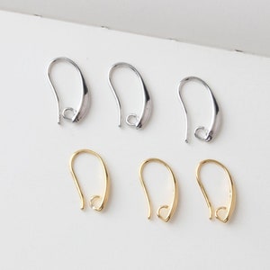 May include: Six earring hooks in two colors: silver and gold. The hooks are curved with a small loop at the bottom for attaching earrings. The silver hooks are in the top row, and the gold hooks are in the bottom row.