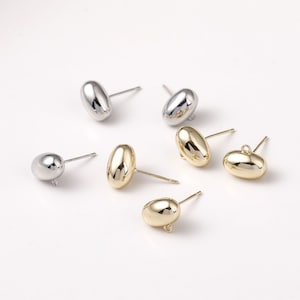 May include: A set of six earring findings in gold and silver. The findings are oval shaped and have a post with a loop on the back.