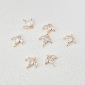 May include: Six gold-tone metal charms with clear crystal accents in the shape of leaves. The charms are perfect for adding a touch of sparkle to jewellery projects.