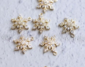 May include: Six gold snowflake charms with clear crystal accents. Each charm has a loop for attaching to jewelry or other crafts.