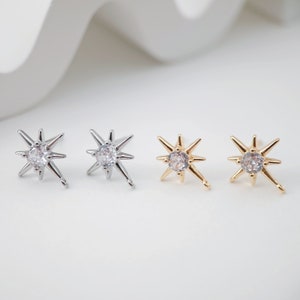 Pode incluir: Um par de brincos em forma de estrela com um centro de cristal transparente. Os brincos estão disponíveis em prata e ouro.
