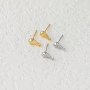 Pode incluir: Quatro brincos de pressão em forma de gota. Dois são dourados e dois prateados. Cada brinco tem um pino para inserção e um pequeno laço na parte inferior da gota.