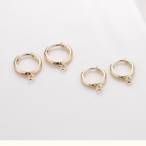 May include: Four gold hoop earrings with a small jump ring attached to the bottom of each hoop.