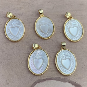 May include: Five gold-coloured pendants with oval, mother-of-pearl faces. Each pendant features a heart design in the centre, surrounded by a decorative border. The pendants have a gold bail at the top for attaching to a chain.