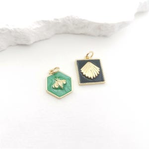 May include: Two gold-toned pendants. One is a green hexagon with a gold bee. The other is a black square with a gold seashell design. Both pendants have a gold border and a small loop for a chain.