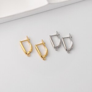 Può includere: Due paia di monachelle per orecchini. Un paio è color oro e l'altro color argento. Gli orecchini hanno un design curvo a forma di D con un piccolo anello nella parte inferiore per attaccare ciondoli o perline. La chiusura a leva è visibile.