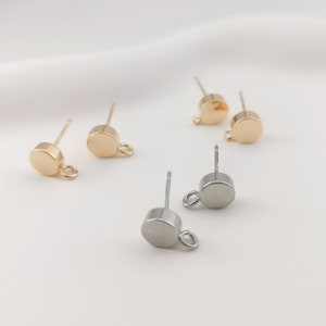 May include: Three pairs of earring findings with a round disc and a jump ring. The findings are in gold and silver.