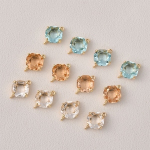 以下が含まれることがあります： 正方形のガラスストーンが付いたゴールドトーンのチャーム10個の詰め合わせ。ストーンはライトブルー、ライトピーチ、クリアの3色です。各チャームにはジュエリーに取り付けるためのループが付いています。