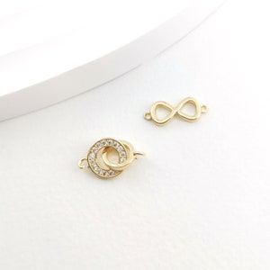 May include: Two gold-tone jewellery clasps, one in the shape of an infinity symbol and the other a double circle with clear rhinestones.