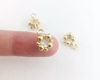 May include: Three gold-toned charms with a clear rhinestone in the center. Each charm has a loop at the top and a smaller loop at the bottom.