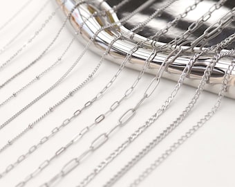 May include: A variety of silver chains of different styles and thicknesses displayed on a silver tray. The chains are arranged in a fan shape, with the longest chain at the top and the shortest chain at the bottom.