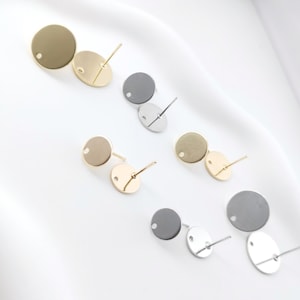 May include: Six pairs of round earring blanks with a hole in the center. The blanks are in three different finishes: gold, silver, and black.