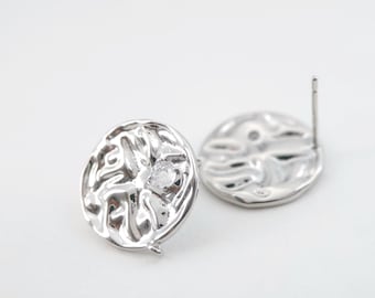 May include: A pair of silver earrings with a textured circular design. One earring features a small clear stone in the center.