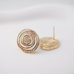 Puede incluir: Un par de pendientes de color dorado con un diseño en espiral. Los pendientes están hechos de metal y tienen un cierre de poste.