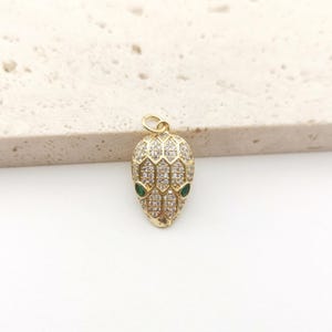May include: Gold-tone snake charm pendant with clear and green cubic zirconia stones.