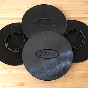 May include: Four black plastic wheel centre caps with the Ford logo embossed on two of them. The centre caps have a ring of small teeth around the centre hole.