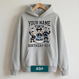 May include: Grey hoodie with a graphic of Mickey Mouse, Donald Duck, and Goofy in hockey gear, with the text "YOUR NAME OFF THE BIRTHDAY BOY". The design includes a birthday cake with the number 4.