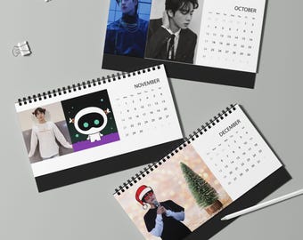 Può includere: Tre calendari da scrivania con rilegatura a spirale che mostrano le pagine mensili di ottobre, novembre e dicembre. Ogni pagina visualizza una griglia di date accanto a ritratti fotografici di una persona, un personaggio e un cappello natalizio.