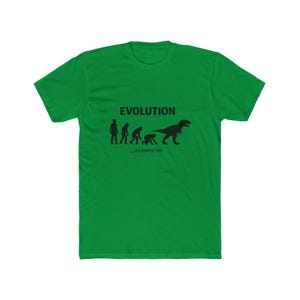 May include: Green t-shirt with the word "EVOLUTION" above a graphic depicting the evolution of humans into a T-Rex. The text "_AS EXPECTED" is below the graphic. The shirt is made of a soft material.