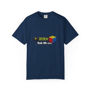 May include: Navy blue t-shirt featuring a graphic of a Rubik's Cube with the text "00:09.99" and "Sub-10 or Bust". The graphic includes a timer and a colorful cube design. The shirt is a short-sleeved crew neck.