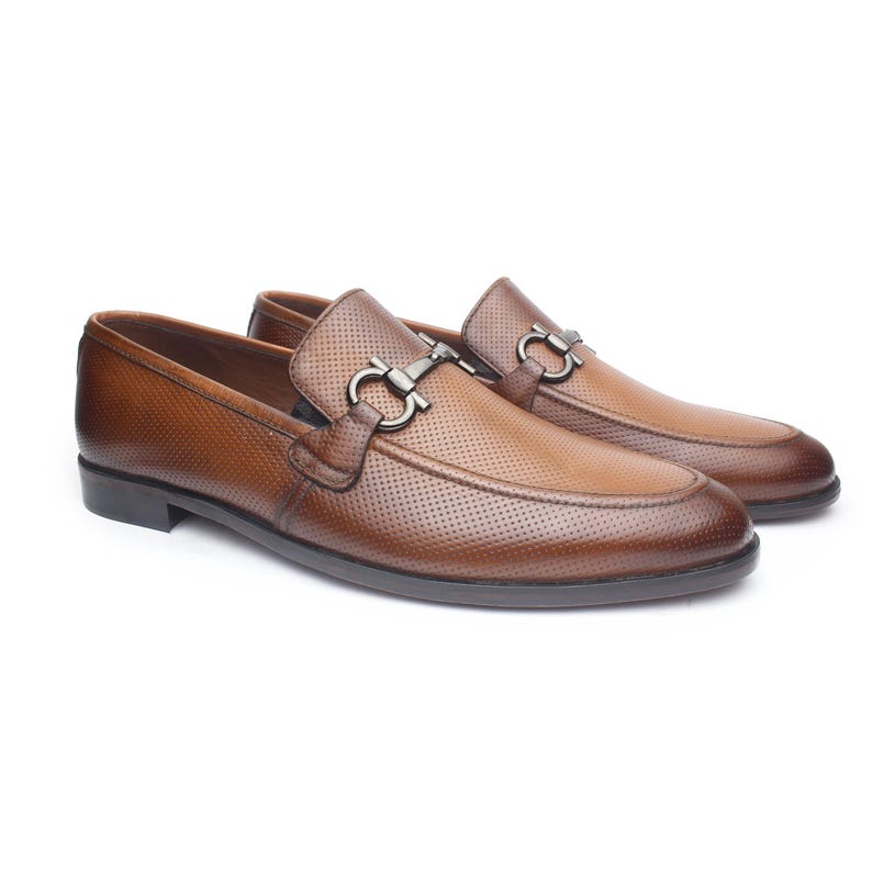 May include: A pair of brown leather loafers featuring a perforated texture across the upper surface and a dark metallic horsebit detail across the vamp. The shoes have a rounded toe, a low heel, and a dark brown sole with visible stitching.