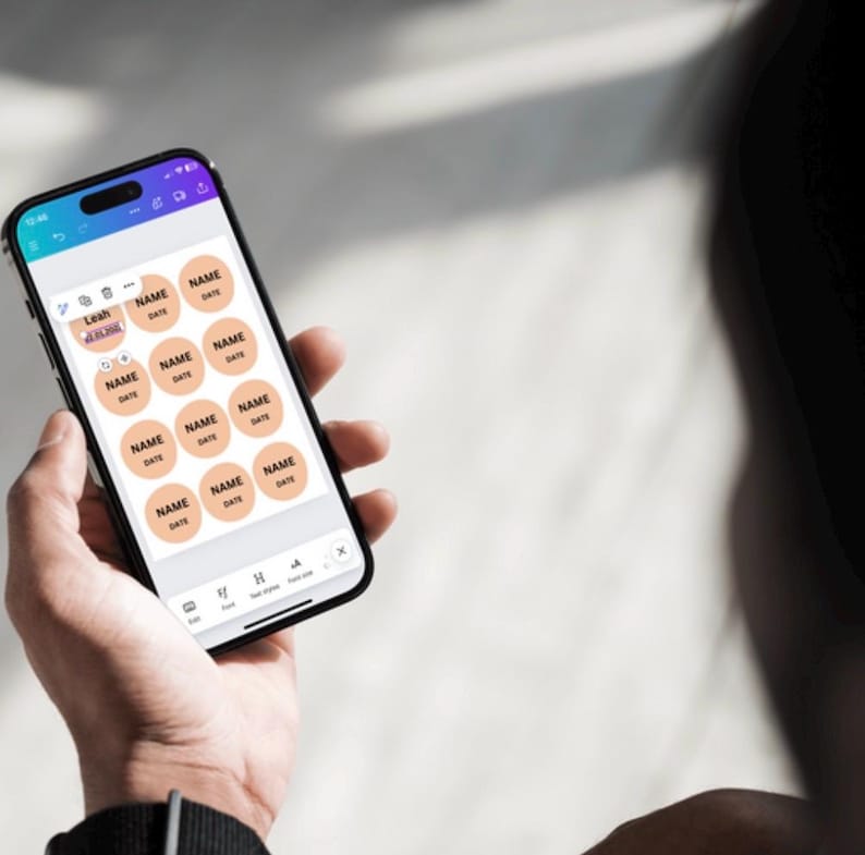 May include: A smartphone screen displaying a digital template for creating personalized labels. The template features a grid of 16 circular labels with the text "NAME" and "DATE" on each label. The labels are peach-colored with black text.