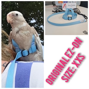 May include: A light blue bird harness with a matching leash, featuring a woven texture, black metal adjustment buckles, and a small white tag labelled EZ-ON. The harness is designed for small birds and is marked as size XXS, ORIGINAL EZ-ON.