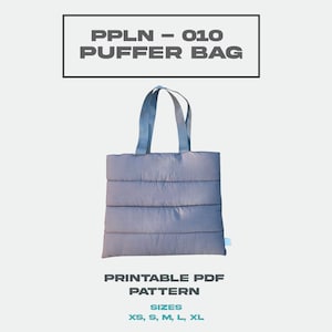 Könnte beinhalten: Eine graue gesteppte Tragetasche mit schwarzen Griffen. Die Tasche hat ein Etikett mit der Aufschrift "PPLN - 010 PUFFER BAG" und die Aufschrift "DRUCKBARE PDF-ANLEITUNG" und "GRÖSSEN XS, S, M, L, XL".