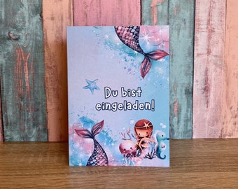 Puede incluir: Una tarjeta azul y rosa con una ilustración de sirena y el texto "Du bist eingeladen!" que se traduce como "¡Estás invitado!" en inglés.