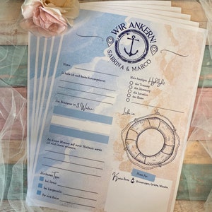 May include: A stack of nautical-themed wedding guest book pages. The design features an anchor, life preserver, and text in blue and brown tones. The text includes "WIR ANKERN!" and the names "SABRINA & MARCO."