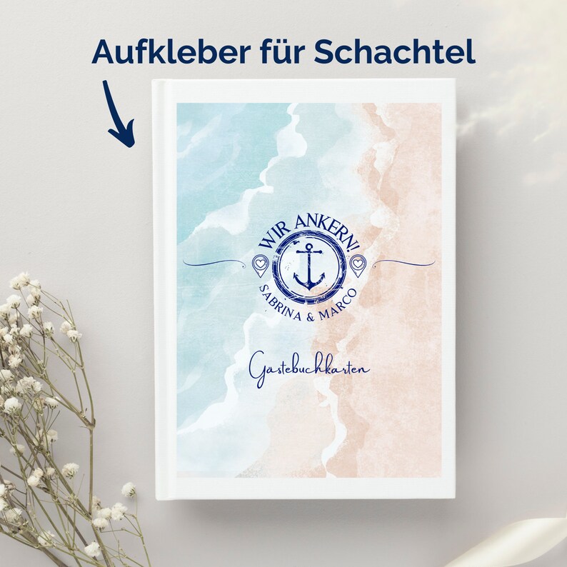 May include: A white guest book with a beach-themed design. The cover features a watercolor illustration of a beach scene in shades of blue and tan, with an anchor and the words "Wir Ankern!" and "Sabrina & Marco". The words "Guestbook Cards" are also visible.
