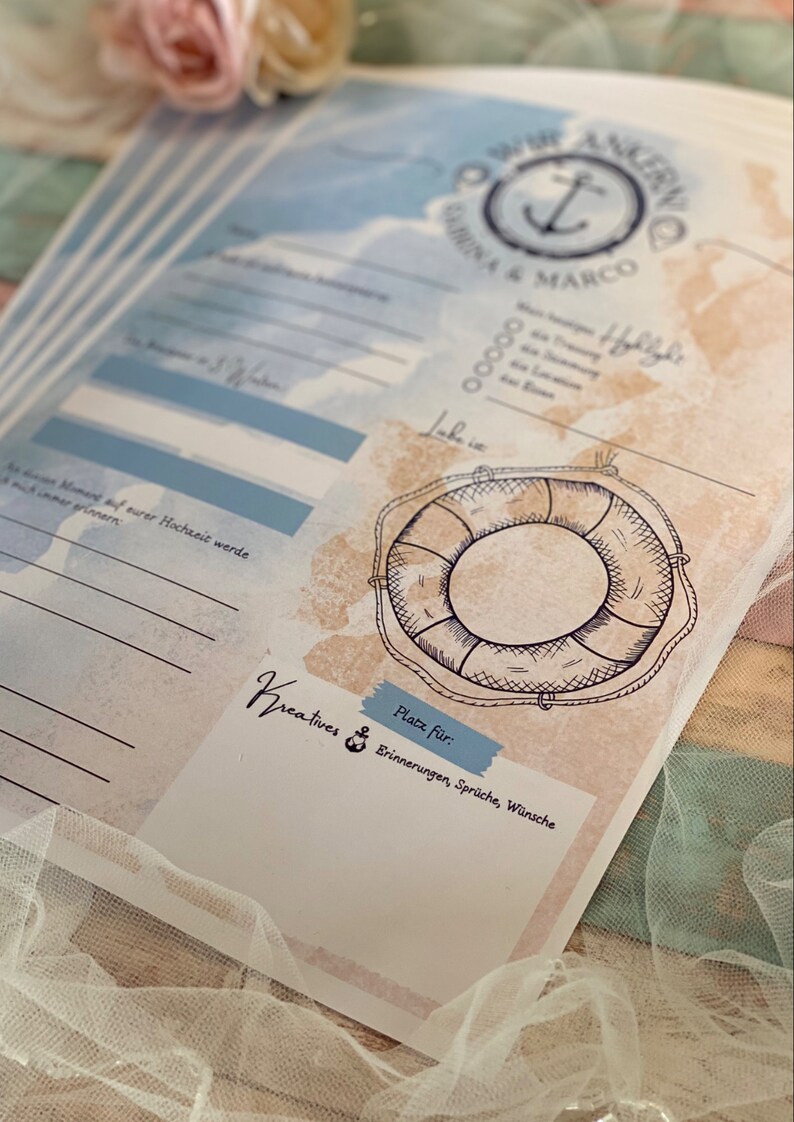 May include: A nautical-themed wedding guest book with blue and beige watercolor backgrounds. The design includes an anchor, a life preserver illustration, and text in German. The book has space for memories, wishes, and quotes.