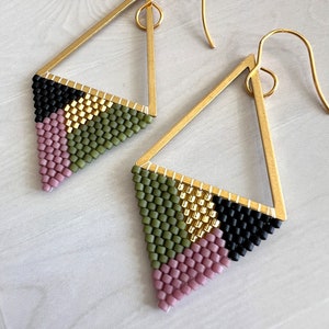 May include: A pair of gold triangle earrings with geometric beaded designs in pink, green, black, and gold.