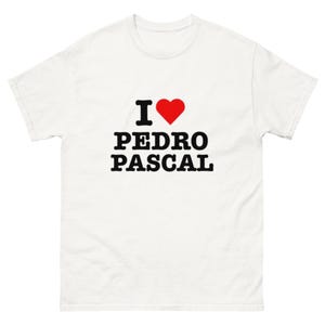Peut inclure: T-shirt blanc avec l'inscription "I ♥ PEDRO PASCAL" en lettres noires et un cœur rouge. Le t-shirt est fait d'une matière douce et a un col rond.