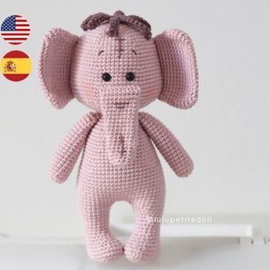 Puede incluir: Un juguete de amigurumi de elefante de crochet rosa con hilo marrón para las orejas y una pequeña nariz de hilo marrón. El juguete tiene ojos de botón negros y una sonrisa cosida.