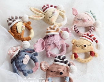 May include: Seven crocheted animal rattle toys with sleeping caps. The toys are in various colors, including brown, pink, blue, and yellow. Each toy has a ring for a handle. The toys are on a white background. @luluptitedoll www.luluptitedoll.com