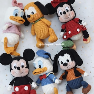 May include: A collection of six crocheted stuffed dolls featuring classic cartoon characters including a white duck with a pink bow, a yellow dog, a mouse with a red dress, a mouse with red shorts, a white duck with a blue shirt, and a tall dog.