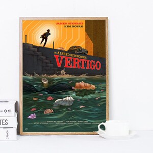 May include: A framed movie poster for Alfred Hitchcock's "Vertigo." The artwork features a man running, a woman in the water, and the title in red. The poster has a vintage aesthetic with a wooden frame.