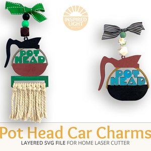 May include: Two coffee pot car charms with the words "Pot Head" on them. The charms are made of wood and have a layered design. One charm is green, brown, and black, and the other is blue, red, and black.