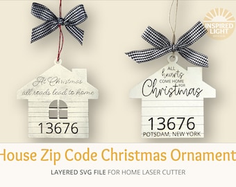 May include: Two white wooden house-shaped Christmas decorations with black and white checked ribbon. The decorations have the text "At Christmas all roads lead to home" and "All hearts come home for Christmas" and the postcode "13676".