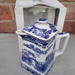 Puede incluir: Jarra réplica en miniatura de cerámica blanca y azul con tapa. La jarra presenta un diseño de paisaje azul y blanco detallado. La tapa y el borde tienen detalles dorados. El embalaje dice "Miniature Maling Replica Jug".