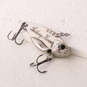 May include: A silver fishing lure with a treble hook and a personalized inscription that reads "Anthony Kwan".