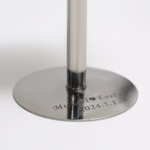 May include: A polished silver cake stand featuring a circular base and a central support. The base is engraved with the names "Michael Evelyn" and the date "2024.5.1". Ideal for presenting cakes or other treats at celebrations.