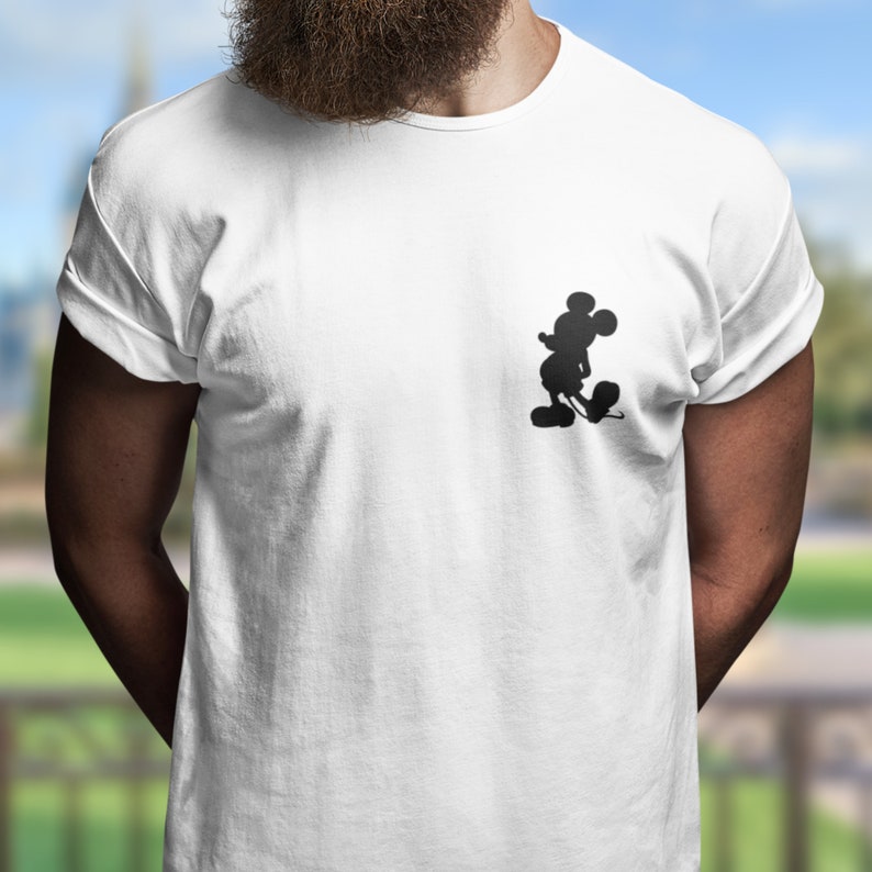 Puede incluir: Camiseta blanca con una silueta negra de Mickey Mouse en el lado izquierdo del pecho.