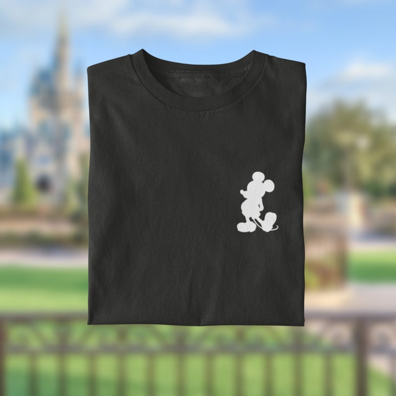 Puede incluir: Camiseta negra con una silueta blanca de Mickey Mouse en el pecho izquierdo.